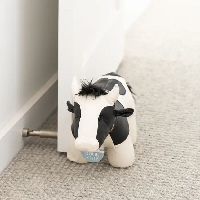 Black and white cow door stop in use holding a door open